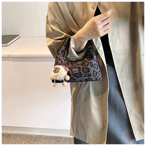 Close-up of leopard print handbag fabric featuring a cute white plush sheep charm