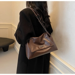 Detailansicht der dunkelbraunen Leder-Umhängetasche mit Metallkette auf dem Modell