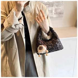 Detail view of dark grey leopard print crossbody bag with cute plush pendant and leather tag