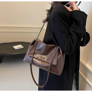 Detail der dunkelbraunen Leder-Shopper mit mattem Finish und stilvollem Metallkettenriemen