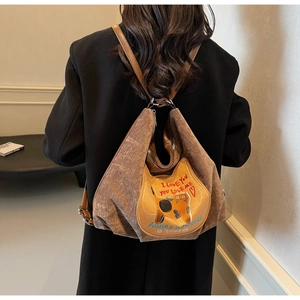 Detail of brown corduroy backpack featuring cat patch embroidery and leather straps