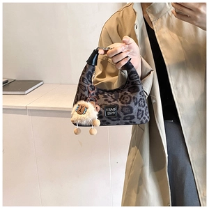 Detail of leopard print hobo bag with black leather handle and plush sheep charm