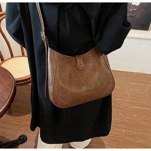 Detail of vintage brown leather hobo bag with contrast stitching and embossed logo