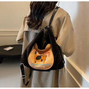 Detail of black corduroy tote bag with orange cat embroidery and leather straps