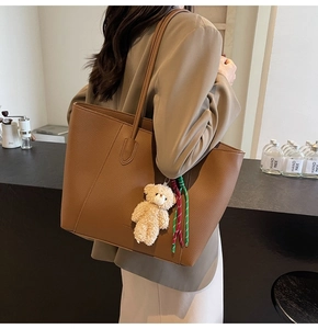 Detail of caramel tote bag showing lychee grain leather and plush bear pendant