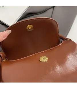 Macro shot of polished brown leather bag with a light gold textured magnetic closure detail