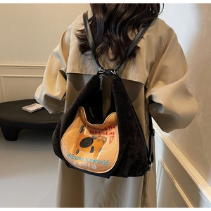 Detail view of a black canvas backpack featuring a cute yellow cat embroidery patch