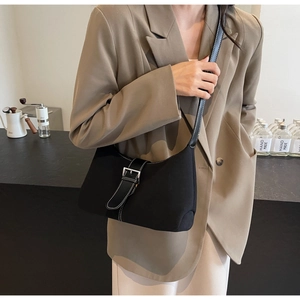 Detail of black suede underarm bag with contrast stitching and silver metal buckle