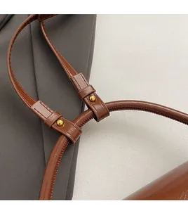 Detail of premium brown glossy leather bag strap with shiny gold rivet and fine stitching