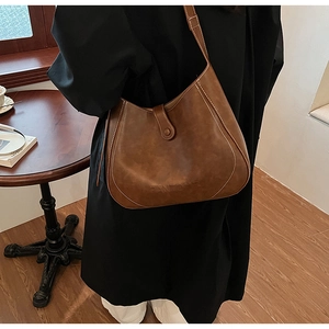 Detail view of the brown leather shoulder bag with buckle closure and bottom logo
