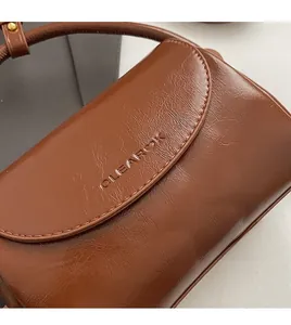 Macro shot of brown crinkled leather texture and embossed logo on vintage handbag