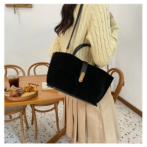 Close-up of black matte tote bag with golden metal clasp in a stylish cafe setting