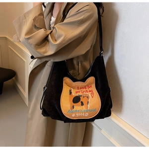 Detail of black corduroy tote bag featuring a large orange cat embroidery and soft texture