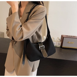 Minimalist black hobo shoulder bag shown on model with chic beige suit and retro background
