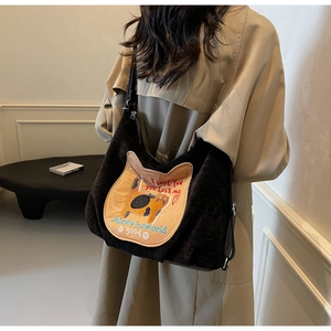 Detail of black corduroy tote bag featuring cute cat embroidery and leather shoulder strap