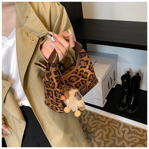 Detail of leopard print crossbody bag with leather handle and cute plush animal charm