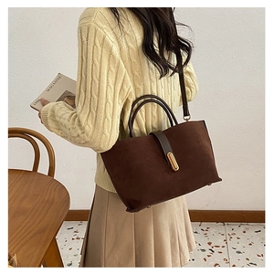 Close-up of deep coffee suede tote bag with gold metal clasp and adjustable shoulder strap