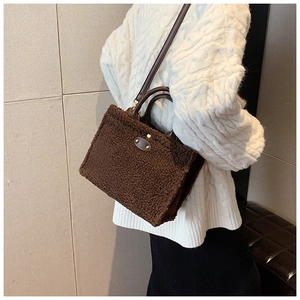 Detail of coffee brown teddy fleece tote bag with leather handles and metallic plate