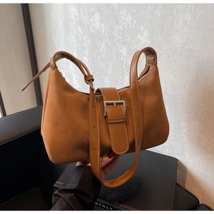 Detail of brown suede shoulder bag featuring white stitching and silver metal buckle