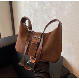 Detailed close-up of dark brown suede handbag with silver hardware and leather straps