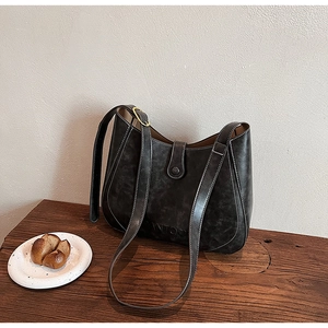 Close-up of vintage leather tote bag with white contrast stitching and embossed logo