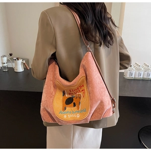 Detail of pink corduroy shoulder bag with embroidered cat pattern and adjustable strap
