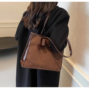 Close-up of brown leather tote bag with bow detail and large capacity on shoulder
