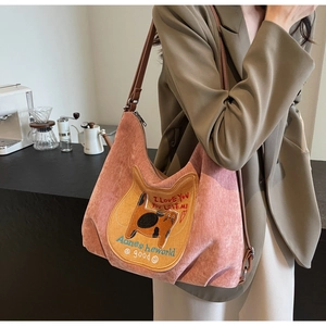 Detail of pink corduroy tote bag featuring cat embroidery and brown leather straps