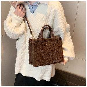Detail of dark brown plush tote bag with leather straps on a knit sweater model