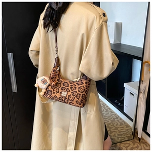 Leopard print hobo bag with a white plush sheep charm on a stylish khaki coat