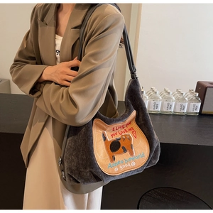 Detail of grey corduroy tote bag featuring an embroidered cat patch and vintage textures