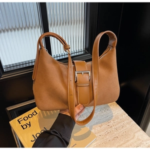 Detailed shot of brown suede shoulder bag with silver buckle and sleek vintage design