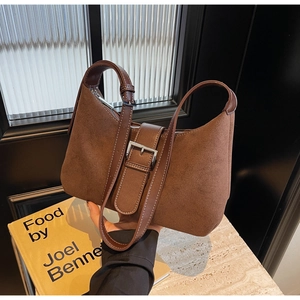 Detail view of brown suede underarm bag featuring silver buckle and leather trim