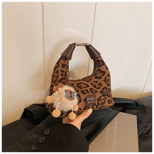 Detailed close-up of leopard print crossbody bag with brown leather handle and sheep charm