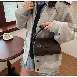 Detailed close-up of glossy dark brown retro square handbag in a lifestyle cafe setting