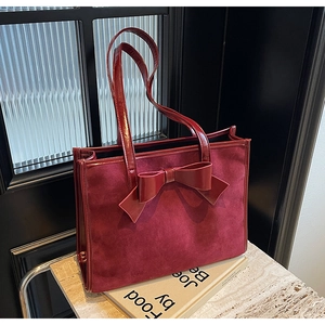 Close-up of wine red tote bag showing faux suede texture and large bow detail