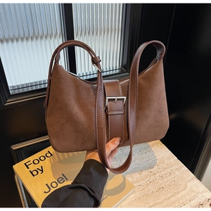 Detailed view of dark brown suede shoulder bag with vintage silver buckle and leather textures