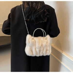 Détail du sac en fausse fourrure crème avec poignée en strass et perles sur un manteau