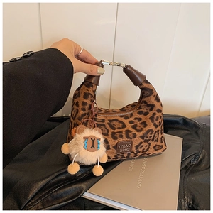 Close-up of leopard print Hobo bag with brown leather handle and plush charm detail