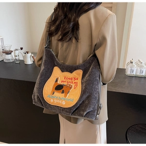 Detail of grey corduroy hobo bag featuring yellow cat patch embroidery and embroidery text
