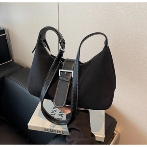 Close-up of black suede hobo bag featuring silver buckle and white contrast stitching