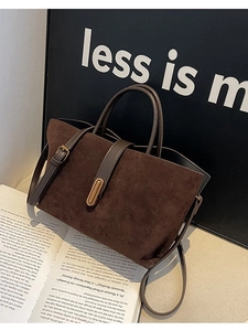 Brown faux suede tote bag with golden lock and adjustable strap in an elegant setting