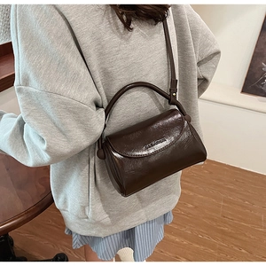 Close-up of a dark brown glossy oil leather mini handbag with a flap and top handle