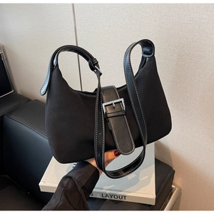 Detail of black canvas crescent bag with white contrast stitching and metal buckle decoration