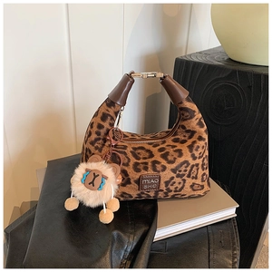 Detail of plush leopard print handbag with leather handle and branded logo tag