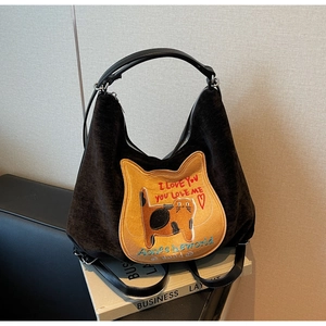 Detailed shot of black corduroy tote with orange cat patch and leather handles