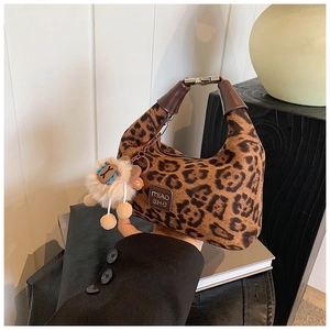 Detail of leopard print crossbody bag with leather brand logo and plush charm