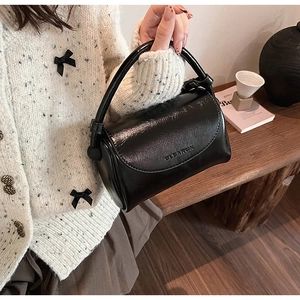 Detail showing high-gloss black leather handbag with GLEARCH brand embossed lettering