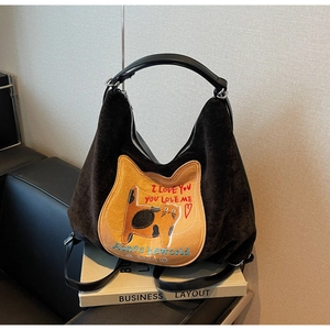 Detail of dark brown corduroy texture and cartoon cat patch on the autumn shoulder bag