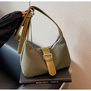 Detail shot of olive green suede shoulder bag featuring a silver pin buckle and smooth leather strap